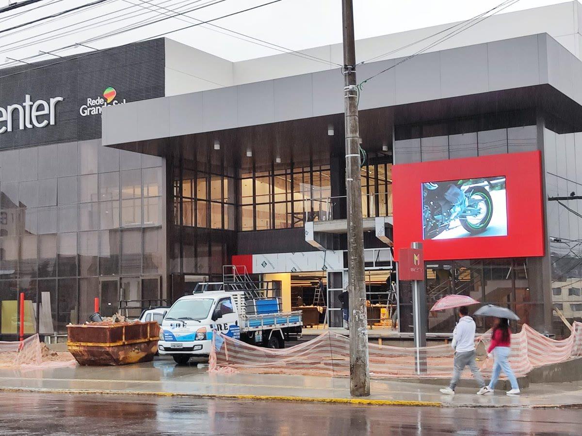 Painel de LED integrado à fachada de loja MaxCenter, estrutura predial em fase final de obra.