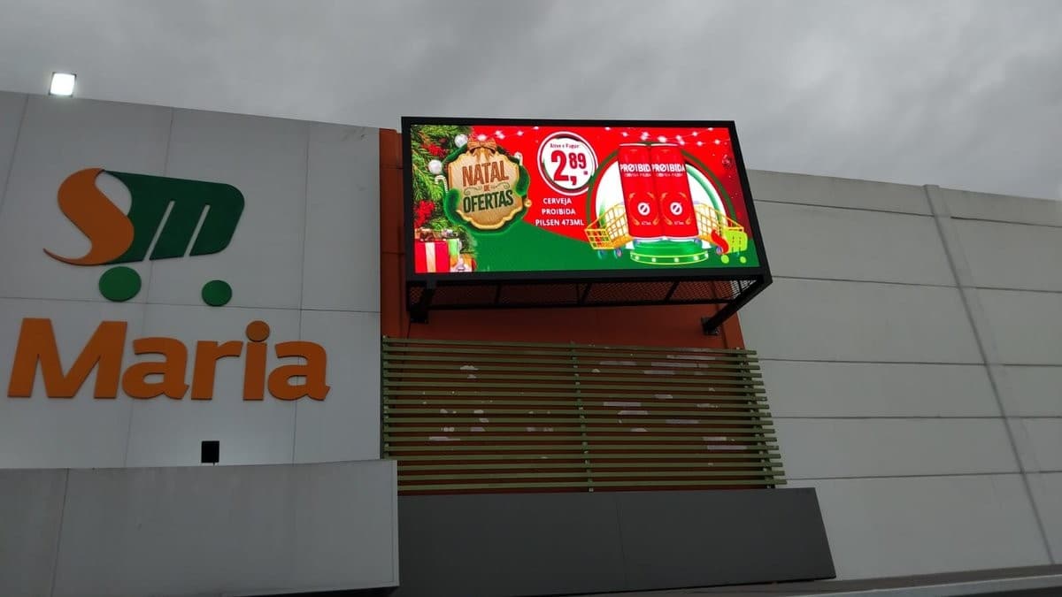 Painel de LED na fachada do Supermercado Santa Maria, exibindo campanha promocional.